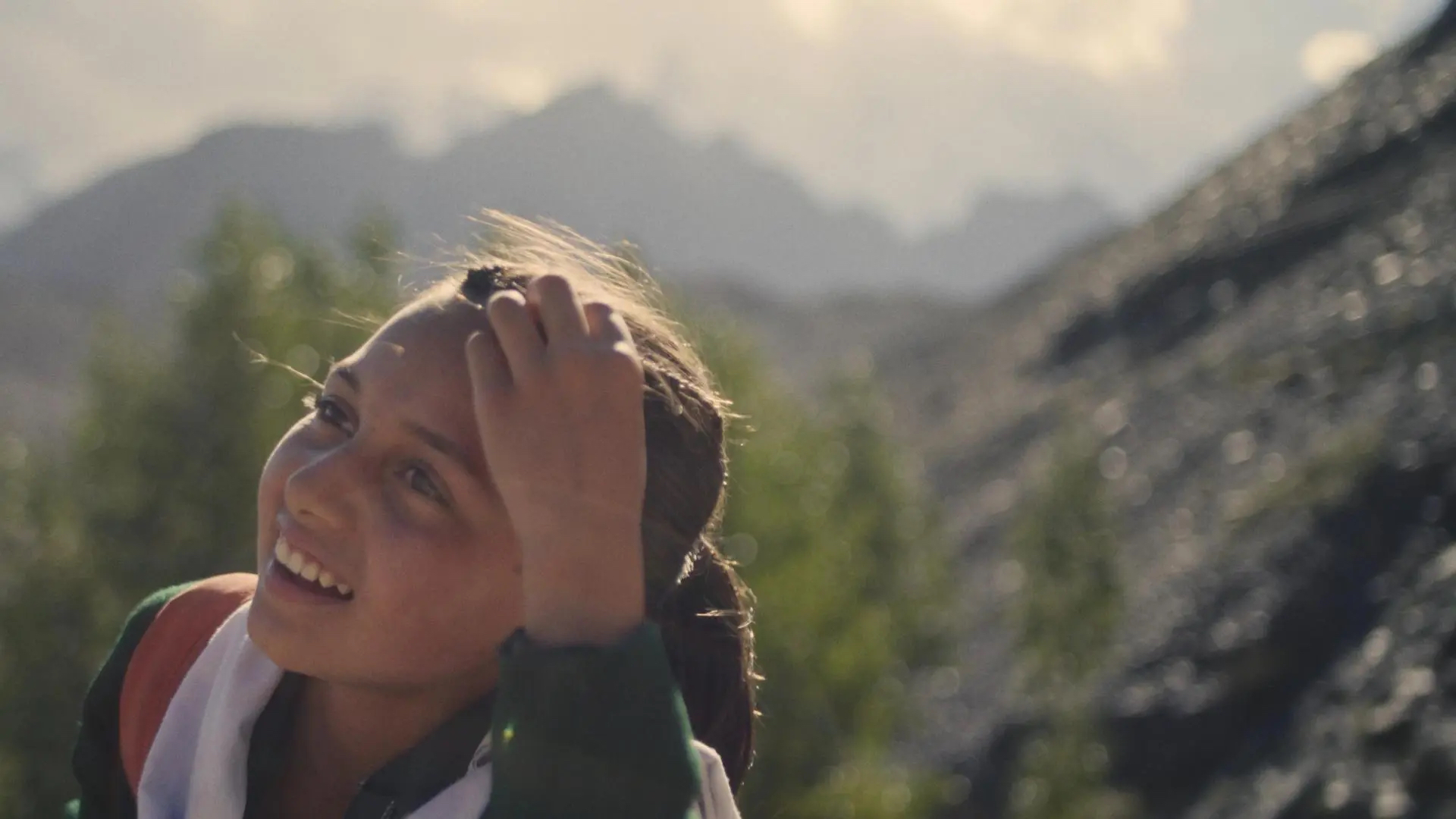 A girl smiles standing on top of a mountain